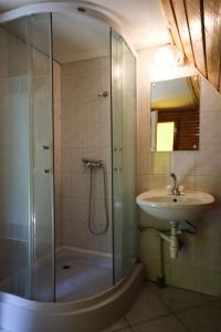 a bathroom with a glass shower and a sink at Erdő Kapitánya Vendégház in Tata