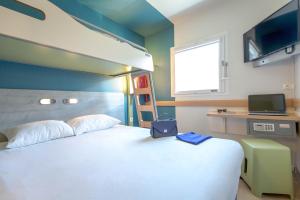 a bedroom with a large white bed and a tv at ibis budget Marseille L'Estaque in Marseille