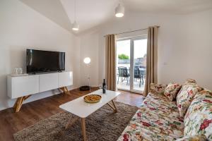 a living room with a couch and a tv and a table at Apartman ZOZZY in Posedarje