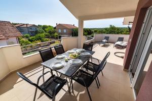 a table and chairs on a balcony with a view at Apartman ZOZZY in Posedarje