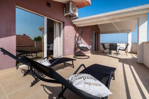 a patio with chairs and tables on a balcony at Apartman ZOZZY in Posedarje