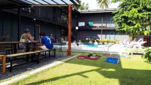 Na-tub Hostel في بان تاي: مجموعة من الناس يجلسون على طاولة بالقرب من مسبح