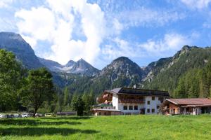 a building in a field with mountains in the background at Alpengasthof Gern Alm in Pertisau