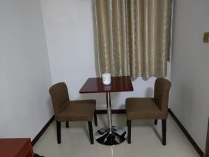 - une table et deux chaises dans une chambre avec fenêtre dans l'établissement CHONG TI HOTEL, à Dili