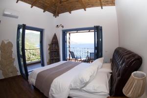 a bedroom with a large bed and a balcony at Villa LeSunLuka Lefkada in Vasiliki