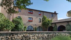 a large brick building with red flowers in windows at B&B LE GINESTRE in Sala Baganza