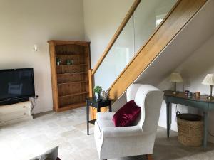 a living room with a white chair and a television at The Old Barn 26 Church Street in Market Deeping