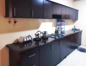 a kitchen with black cabinets and a black counter top at Nimal's Home in Anuradhapura