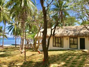 a house on the beach with a thatch roof at Moon Beach Villas El Nido in El Nido
