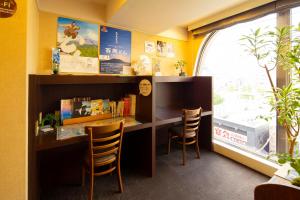 a room with a desk with chairs and a window at Hotel New Nishino in Kagoshima