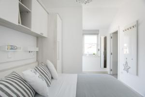 a white bedroom with a large bed with striped pillows at Apartment Movie in Primošten