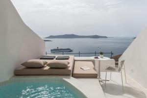 a balcony with a bed and a table and a pool at Enigma Suites in Fira