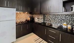 eine Küche mit schwarzen Schränken und einem weißen Kühlschrank in der Unterkunft Devmoon apartment - A Big & beautiful unit in the South of Jakarta in Jakarta