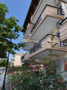 un bâtiment avec des balcons et des fleurs dans une rue dans l'établissement helios apartmenthouse, à Olympiakí Aktí