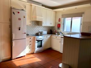 康普特的住宿－Casa na Comporta，厨房配有白色橱柜和白色冰箱。