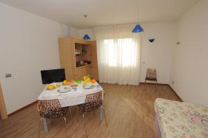 un salon avec une table avec des chaises et une télévision dans l'établissement Residence Piemonte, à Sesto San Giovanni