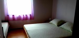 a bedroom with a bed and a window with pink curtains at Sunset Zaglav Apartment in Martinšćica