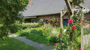 a garden in front of a brick house with roses at Bauernhof Barlo in Bocholt