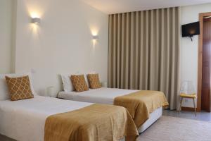 a hotel room with two beds and a chair at Enjoy Viana - Guest House in Viana do Castelo