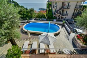 a swimming pool with an umbrella and a building at Apartments Kentera LUX in Sveti Stefan