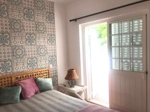 1 dormitorio con 1 cama junto a una ventana en Villa c/ piscina próxima da praia en Cabanas de Tavira