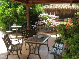 un patio con bancos, una mesa y flores en Hotel Rural La Casona del Fraile, en Colunga
