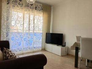 ein Wohnzimmer mit einem TV und einem Fenster in der Unterkunft ATICO DUPLEX PLAYA in Benidorm