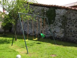 a swing set in a yard next to a wall at Hotel Rural La Casona del Fraile in Colunga