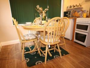 cocina con mesa de madera y sillas en Grockle Nook Holiday Apartment, en Brixham