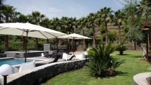 Un patio con sillas y sombrillas y una piscina. en Holiday Homes Borgo Papardo, en Giarre