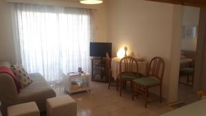 a living room with a table and chairs and a television at Corinthia Premium Apt - A Jewel next to the sea in Pyla