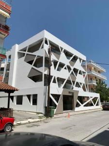 a large white building on the side of a street at Villa Hara Suites in Paralia Katerinis