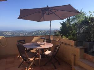 a table and chairs with an umbrella on a balcony at Saberic in Vence