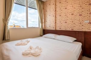 a bed with white towels on it with a window at Scala Hostel in Bangkok