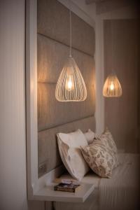 two lights hanging over a bed with two pillows at Dora Apartments in Agia Pelagia