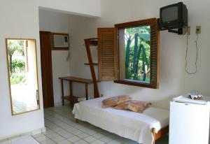 a bedroom with a bed and a tv on the wall at Pousada Girassol in Itacaré