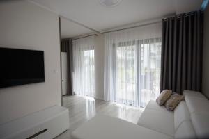 a living room with a white couch and a flat screen tv at Gardenia Sea Side MARTINA 2 Dziwnów in Dziwnów