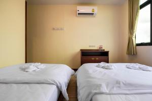 two beds in a room with white sheets at Scala Hostel in Bangkok
