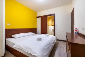 a bedroom with a large bed with a yellow wall at Scala Hostel in Bangkok