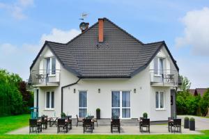 a white house with a black roof and chairs at Villa-Alexandra-Mielenko in Mielenko