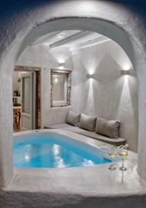 a pool in a room with a couch and two wine glasses at Marble Sun Villa with Jacuzzi by Caldera Houses in Oia