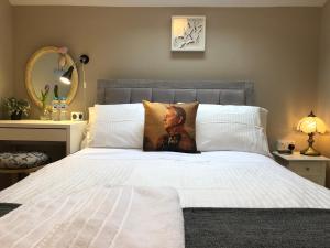 um quarto com uma cama branca com um retrato em Picturesque Village House em Aghnablaney