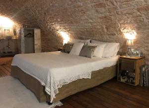 sypialnia z dużym łóżkiem w ceglanej ścianie w obiekcie Maison Santarosa w mieście Castellana Grotte