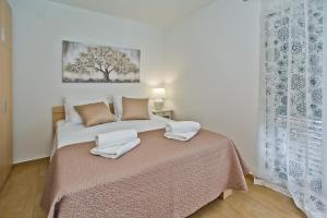 a bedroom with a bed with two towels on it at Luxurious Apartments Maslina with Beach in Milna