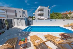 a villa with a swimming pool and two lounge chairs at Villa Mel Mari luxury apartments with pool in Novalja