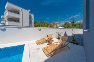 two chairs and a table next to a swimming pool at Villa Mel Mari luxury apartments with pool in Novalja