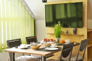 a dining room table with chairs and a large screen at Gästehäuschen-Hösbach in Hösbach