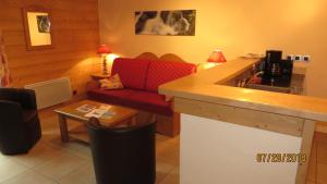 レ・コンタミンヌ・モンジョワにあるアルパイン ロッジ 7のリビングルーム(赤いソファ、テーブル付)