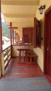 a porch with a wooden picnic table and a window at Casutele Likas in Lacu Rosu +29 photos