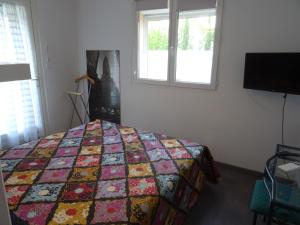 a bedroom with a quilt on a bed with a window at L'Escala in Argelès-sur-Mer